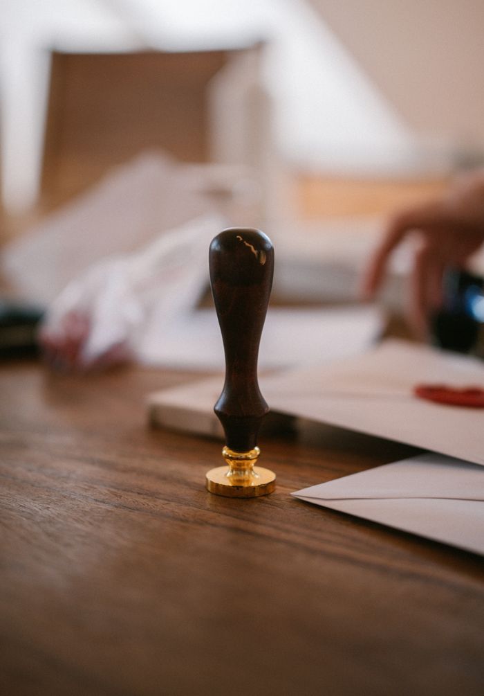 service-01 A close-up of a vintage wax seal stamp on a wooden desk with envelopes, conveying an old-world charm.