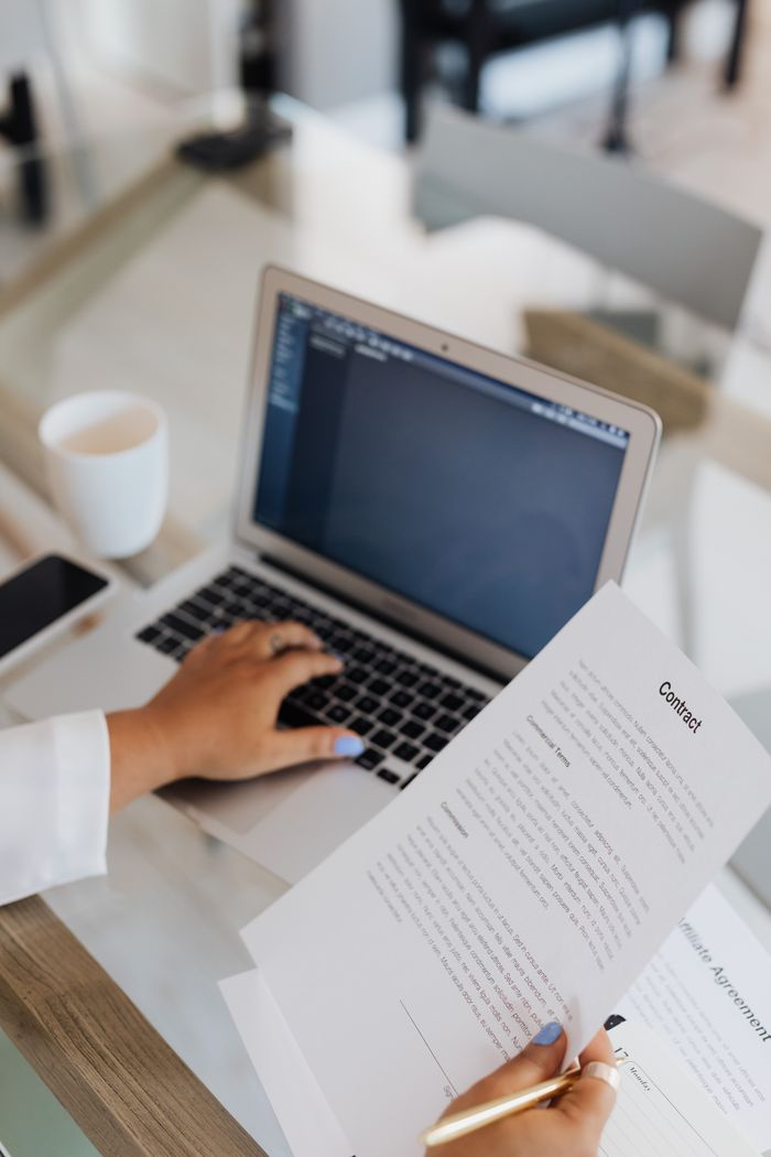 featured-images-03 A person reviewing a contract on a laptop in a modern office setting.