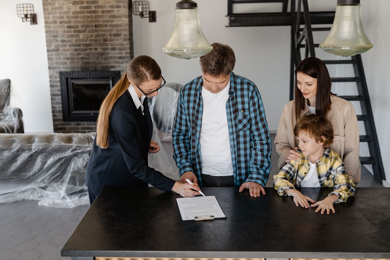 why-choose-us-01 Happy family signing a real estate contract with agent inside their new home.